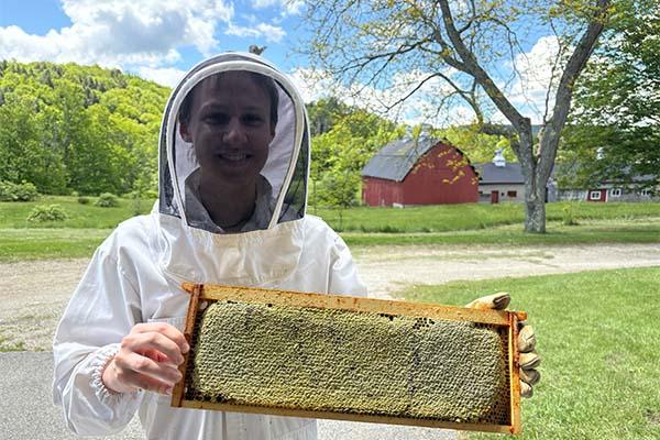 A MCLA beekeeper holds a board of bees 