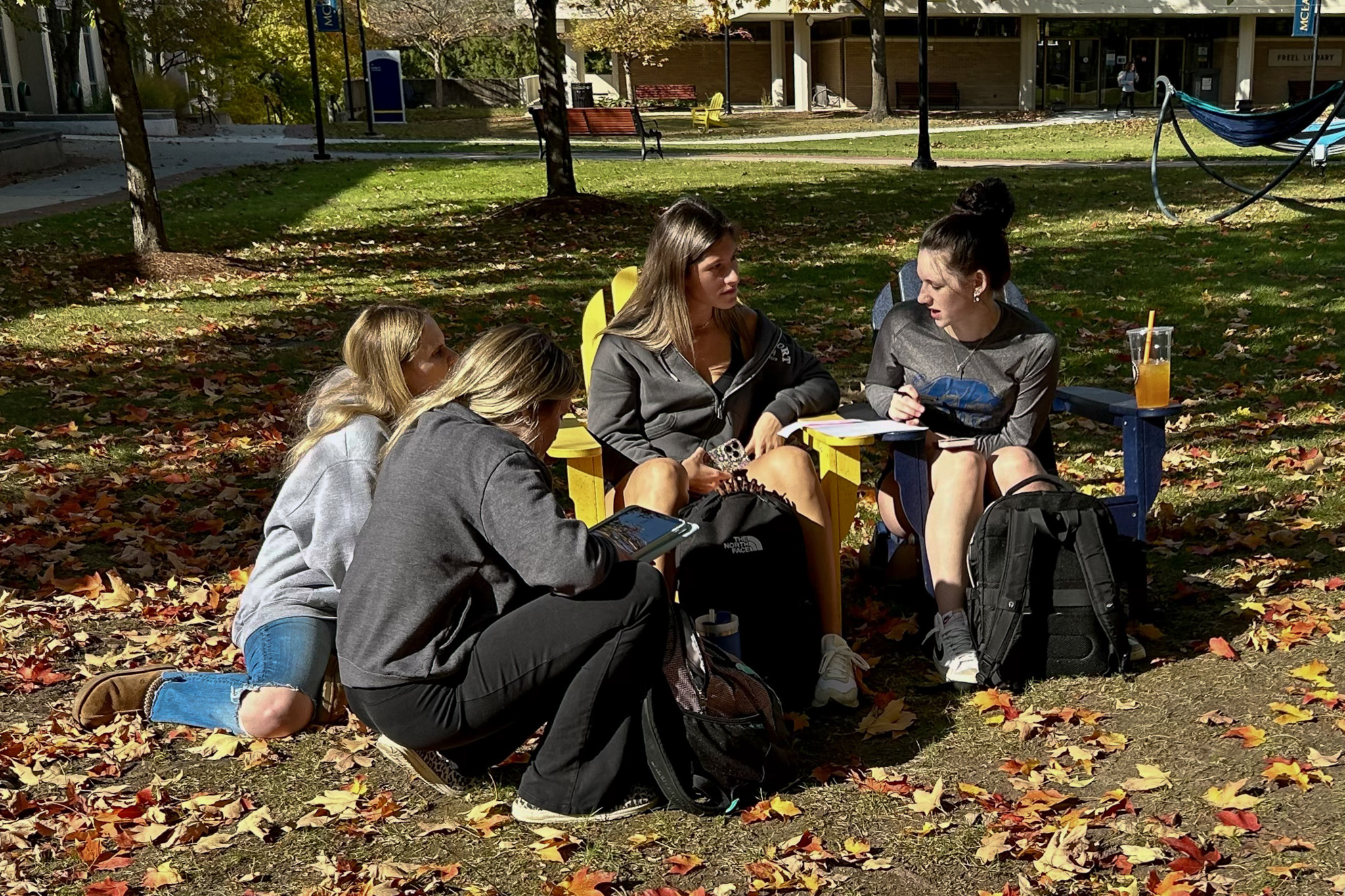 Four students sitting outside on the quad during the fall.