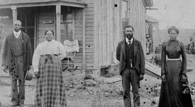 Two Black couples, men and women, standing in front of house