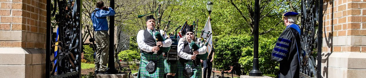 Bagpipe players at graduation with President Birge at the gate