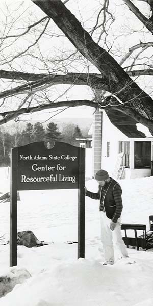 MCLA Resource Center sign in winter with a person next to it.