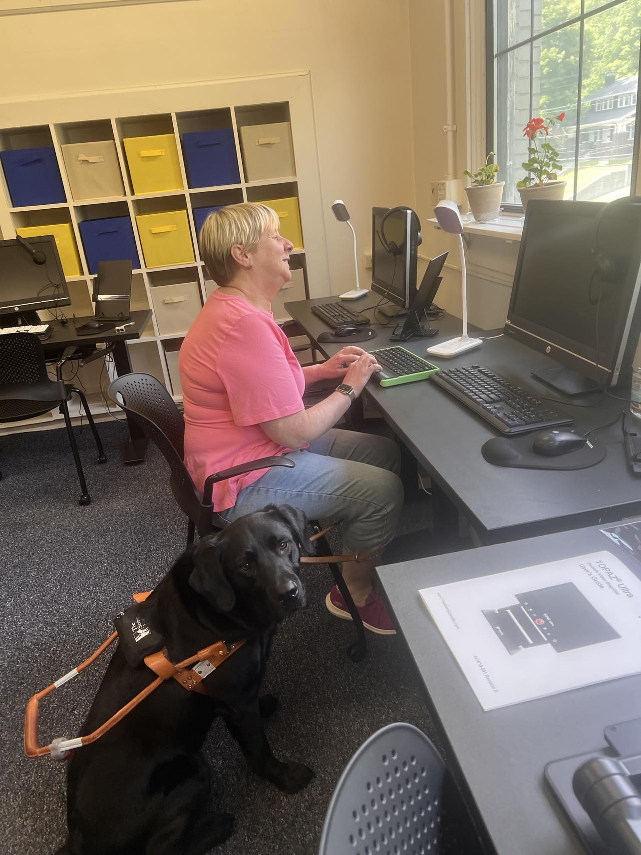 Student at Computer in Assistive Lab with black service dog