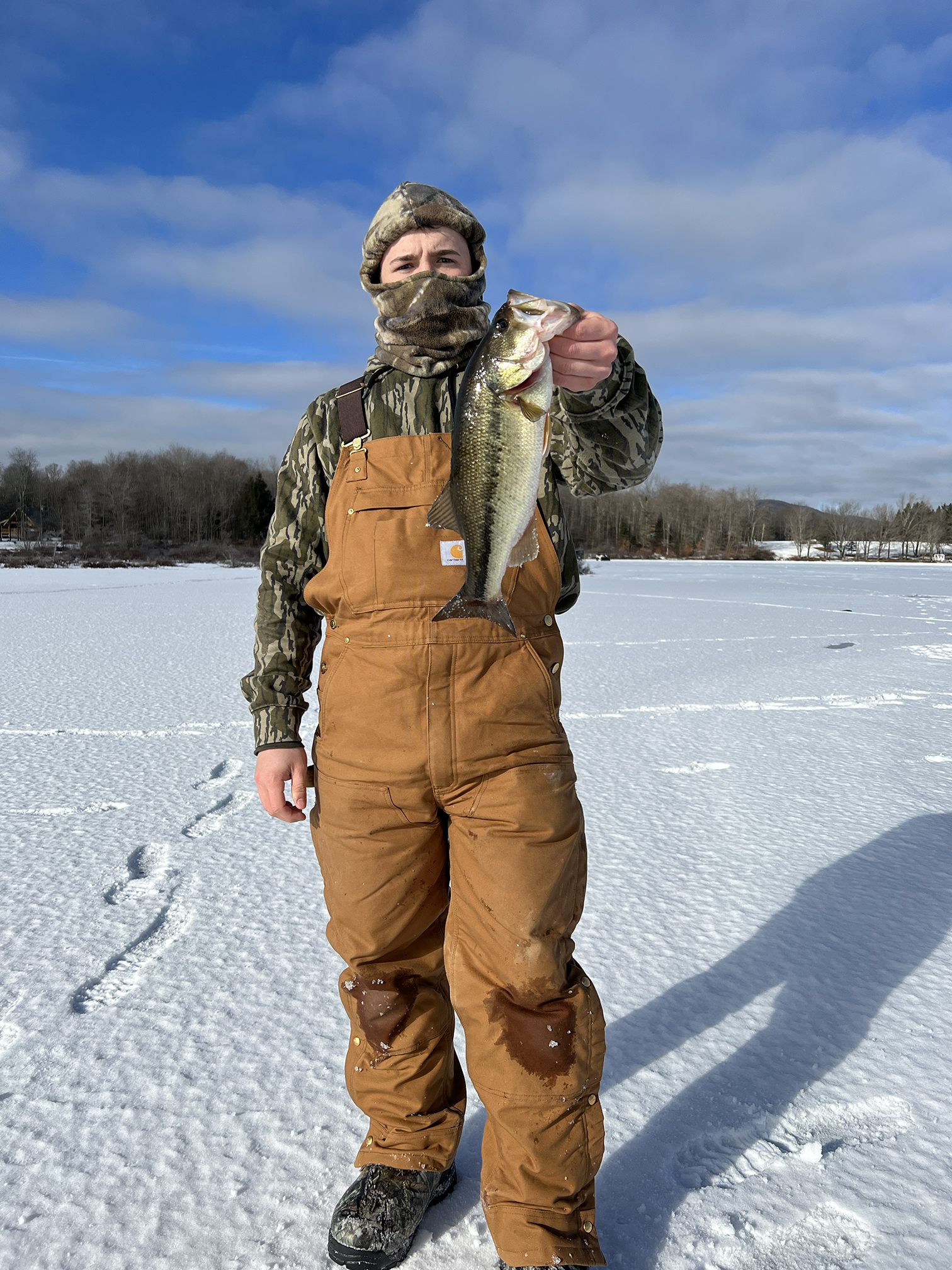 Nathan Haley stands with a largemouth bass he caught while ice fishing at Sadawga Lake in Vermont.