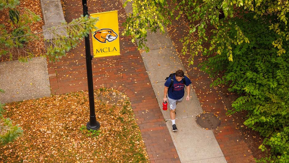 Aerial view of a student walking on sidewalk on the MCLA campus
