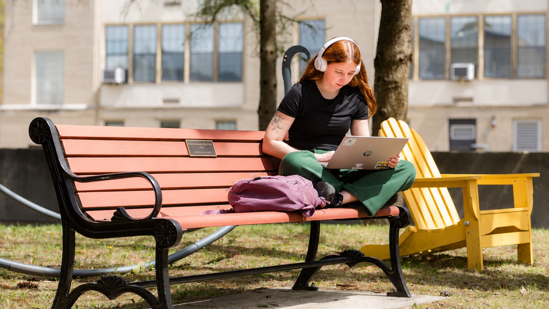 MCLA campus with a student on a bench working on their laptop
